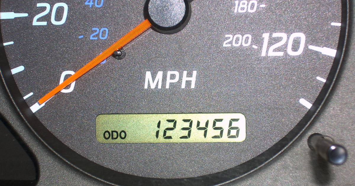 A close-up of a car's odometer. The speed gauge is pointing at 0 while the odometer reads 'ODO 123456.'